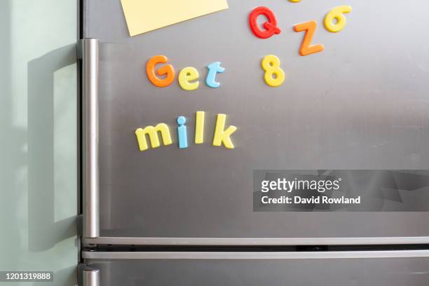 colourful  magnetic letters on a silver fridge with words get milk with blank sticky notes - lettera magnetica foto e immagini stock