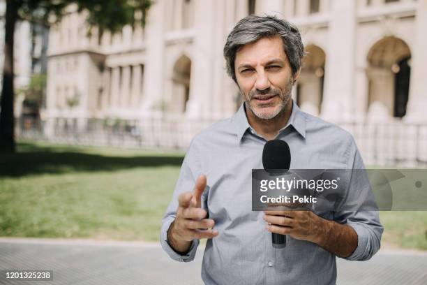 journalist with microphone on the city streets - newscaster stock pictures, royalty-free photos & images