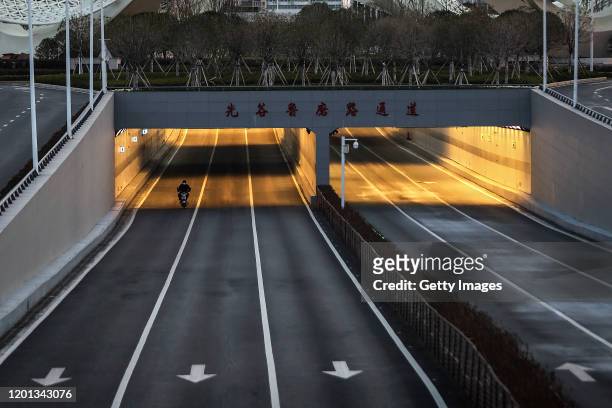 Man cycling bike in the empty street at Optical Valley on February 16, 2020 in Wuhan, Hubei province, China. Flights, trains and public transport...