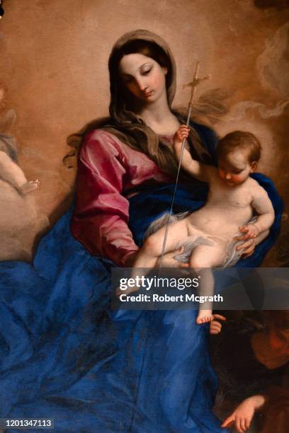 virgin mary, mother of jesus, holds him as a baby with a crucifix, looking down from atmospheric heavenly clouds. - mary moody stockfoto's en -beelden