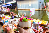 Sweet coconut ice cream in the fresh coconut and plastic spoon at Damnoen Saduak floating market
