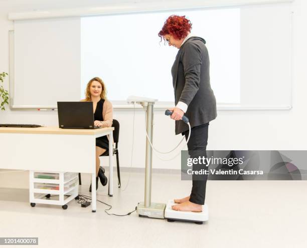 nutritionist and patient using a segmental multi frequency body composition analyser for a full body scan. - man standing full body stock-fotos und bilder
