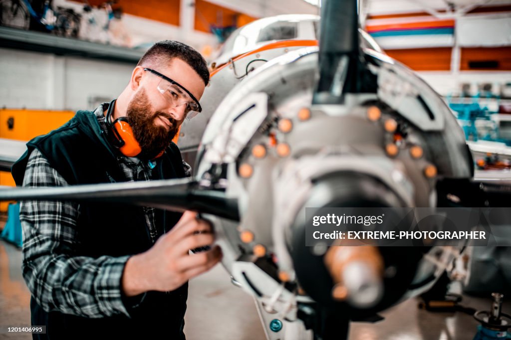 Aircraft engineer repairing a small front-engine airplane disassembled in a hangar