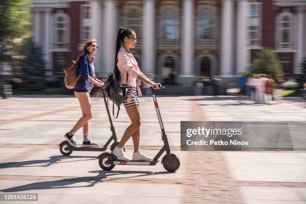 vriendinnen die e-scooters in de stad berijden - mobility scooters stockfoto's en -beelden