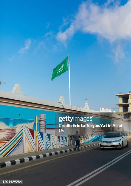 Saudi arabian flag in front of a fresco, Asir province, Abha, Saudi Arabia on January 3, 2020 in Abha, Saudi Arabia.