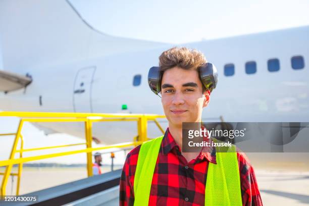 flughafen-bodendienst, junger mann vor flugzeug - airport ground crew uniform stock-fotos und bilder