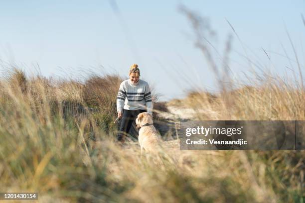 young woman with her dog on the beach - sand dune stock pictures, royalty-free photos & images
