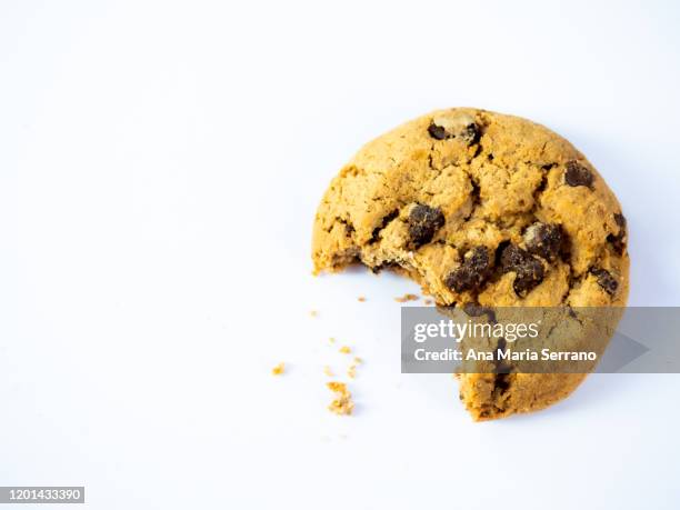 a homemade chocolate cookie with a bite and crumbs on a white background - eaten foto e immagini stock