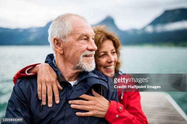 senior couple tourist standing by lake in nature on holiday, hugging. - husband stock pictures, royalty-free photos & images