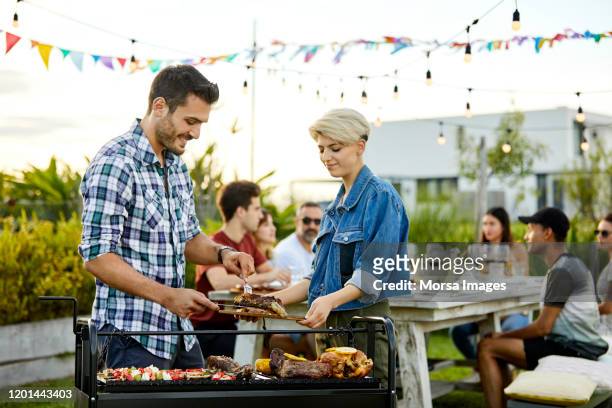 man serving meat prepared on grill during asado - argentina traditional food stock pictures, royalty-free photos & images