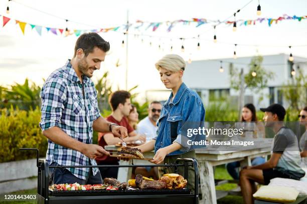 man serving meat prepared on grill during asado - backyard bbq imagens e fotografias de stock