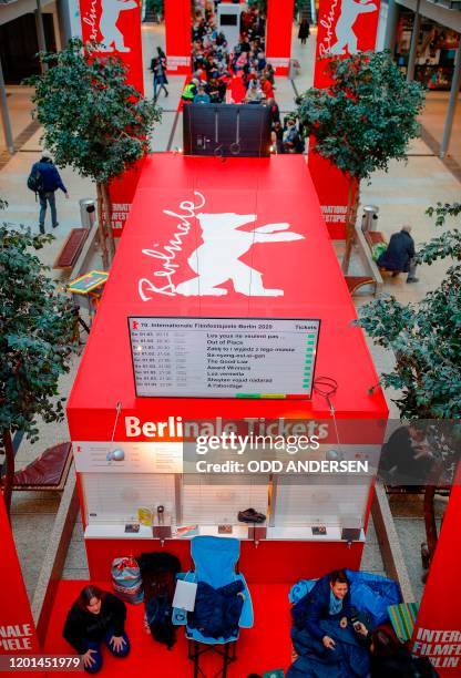 People sit on the floor or on folding chairs as they queue for the 70th Berlinale film festival tickets to go on sale at the Potsdamer Arkaden mall...