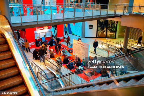 People sit on the floor or on folding chairs as they queue for the 70th Berlinale film festival tickets to go on sale at the Potsdamer Arkaden mall...