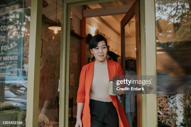 on the move to go after getting hot drink at the coffee shop of thai interior designer women - woman walking out door stock pictures, royalty-free photos & images