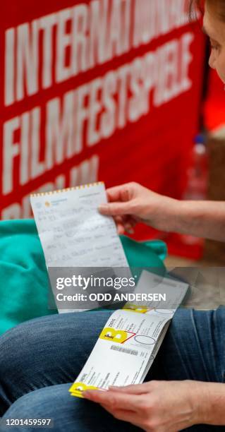 Festival goer checks out the purchased tickets for the 70th Berlinale film festival as the sale starts at the Potsdamer Arkaden mall in Berlin on...