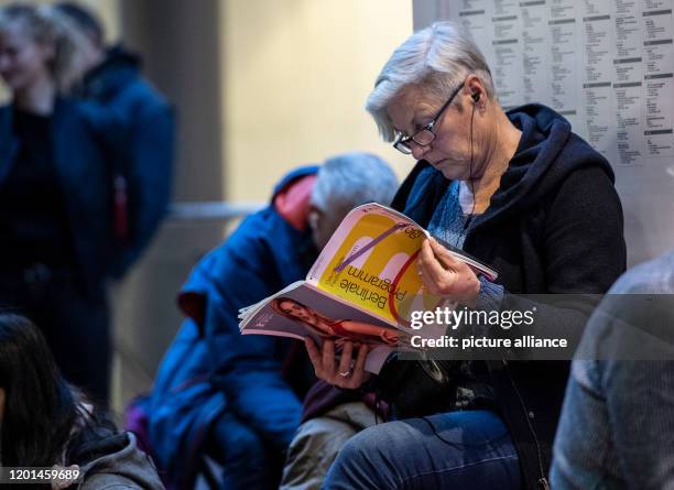 February 2020, Berlin: A woman is sitting in the Potsdamer Platz Arkaden, reading the Berlinale programme, waiting for the start of ticket sales for...