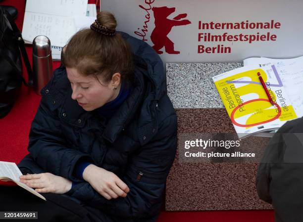 February 2020, Berlin: A woman is sitting reading in the Potsdamer Platz Arkaden, waiting for the start of ticket sales for the International Film...