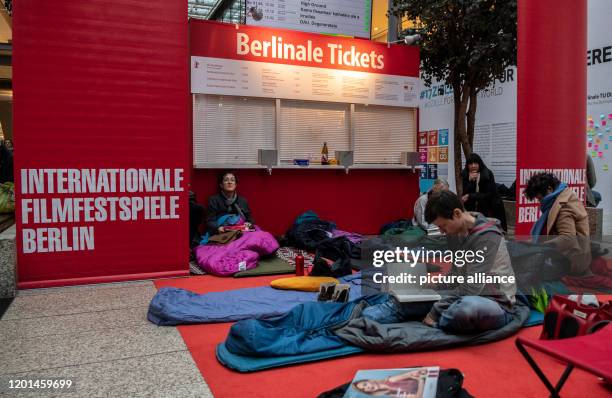 February 2020, Berlin: Film lovers are sitting on sleeping mats and sleeping bags in the Potsdamer Platz Arkaden in front of a still closed box...