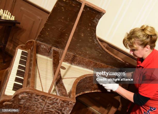 February 2020, Saxony-Anhalt, Halle : Dust on a harpsichord made of solid and dark chocolate is removed by head chocolatier Claudia Schulz-Heimann...