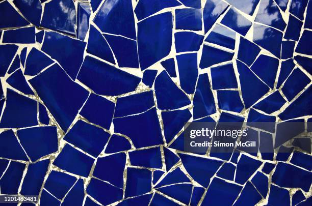 wall covered in a mosaic of broken dark blue glazed tiles - mosaïque photos et images de collection