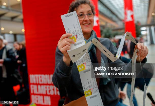 Festival goer checks presents her purchased tickets for the 70th Berlinale film festival as the sale starts at the Potsdamer Arkaden mall in Berlin...