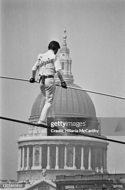 German tightrope walker Franz Burbach carrying a balancing pole as he walks the tightrope, the dome of St. Paul's Cathedral visible beyond, over the...