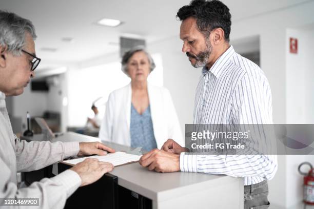 mature men patient on hospital reception - entering hospital stock pictures, royalty-free photos & images