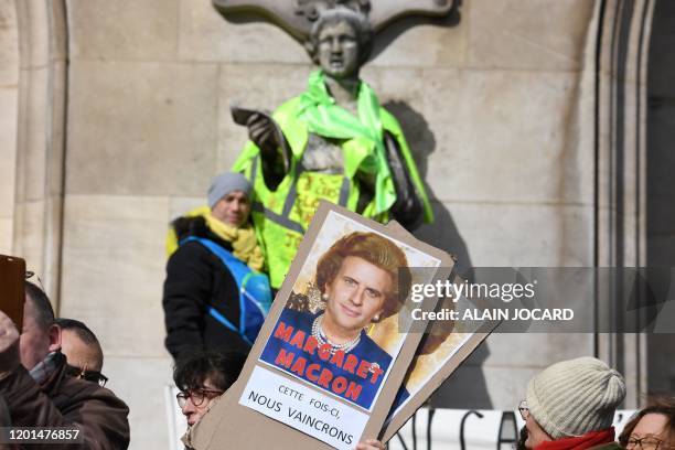 Protester holds a placard reading "Maragaret Macron, this time we will win" under a photomontage of both late British Prime Minister Margaret...