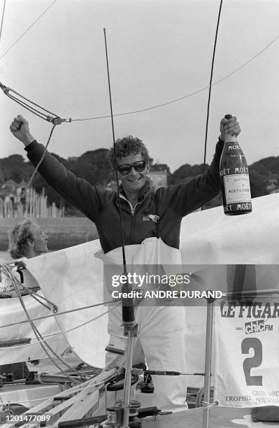 Le navigateur français Christophe Auguin, vainqueur de la course en solitaire à la voile du Figaro, brandit une bouteille de champagne à son arrivée...