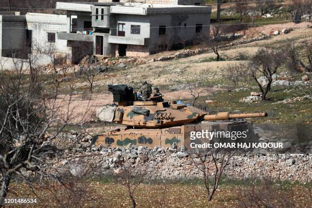 Turkish military M60T tank drives through the village of Matarim in the south of Syria's northwestern province of Idlib, near the M4 motorway that...