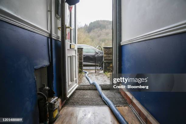 Hose pumps flood water from inside a house in Nantgawr, U.K., on Monday, Feb. 17, 2020. U.K. Weather forecasters issued the countrys first red...