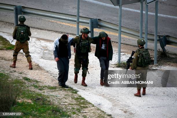 Israeli soldiers detain two Palestinians in the village of Ras Karkar, near Ramallah in the occupied West Bank on February 17 reported to be...