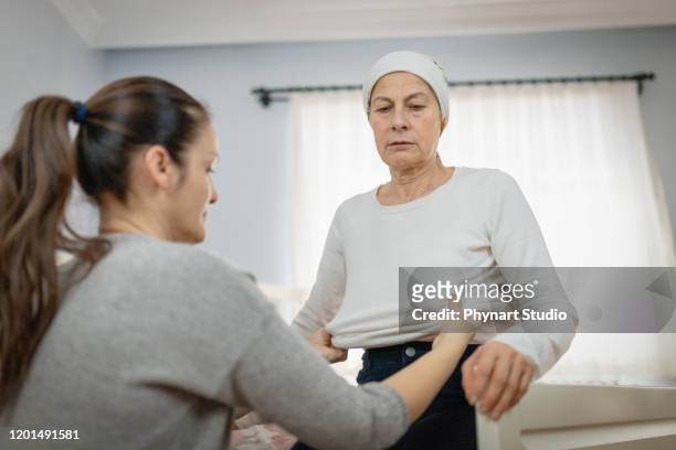 woman who dresses her sick and tired mother - cancer illness stock pictures, royalty-free photos & images