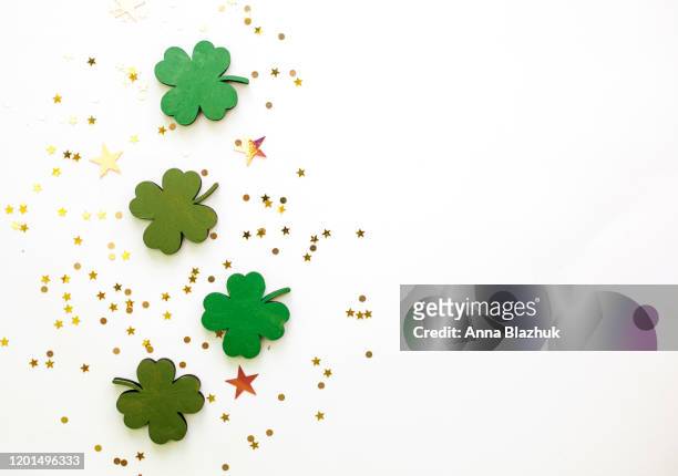 green clovers or shamrocks and confetti white background for st. patrick's day holiday - st patricks day stock pictures, royalty-free photos & images