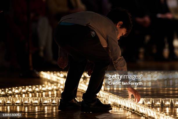 Young member of the congregation places a candle alongside 600 others that are set out as a Star of David on the floor of the Chapter House of York...