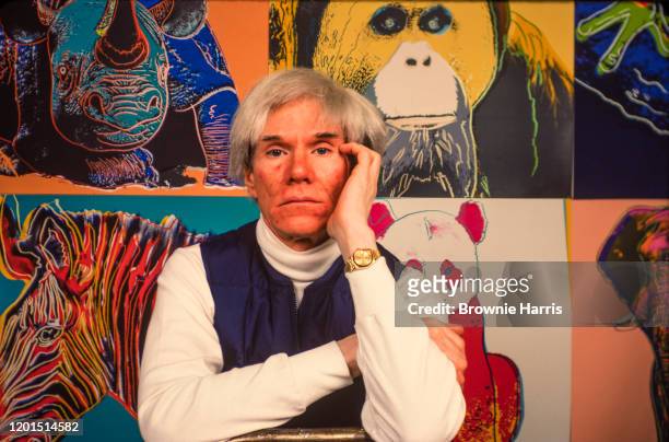American Pop artist Andy Warhol sits in front of several paintings in his 'Endangered Species' at his studio, the Factory, in Union Square, New York,...