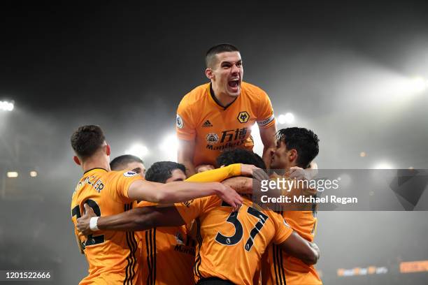 Conor Coady of Wolverhampton Wanderers jumps on his team-mates as they celebrate Raul Jimenez scoring his team's first goal during the Premier League...