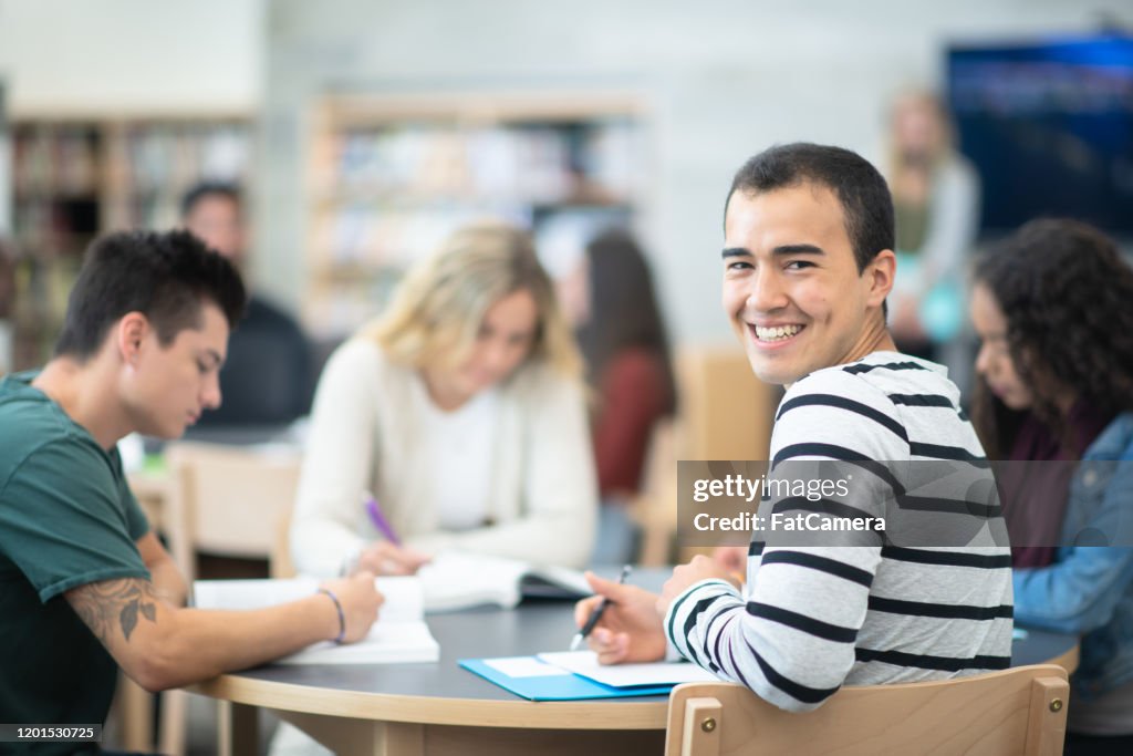 Male Student Smiling at a Table With His Peers stock photo