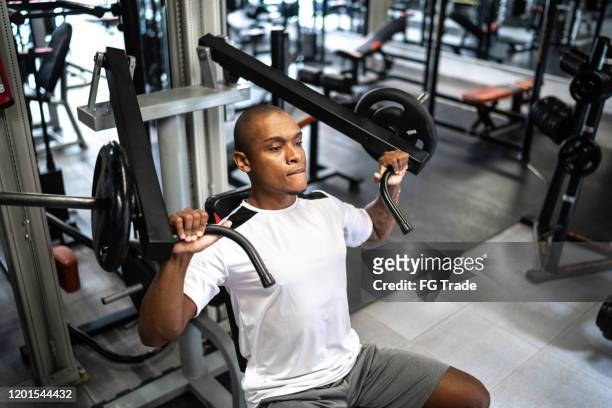 man doing strength workout exercise in gym - health club stock pictures, royalty-free photos & images