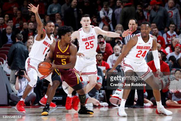Luther Muhammad, Andre Wesson and Kyle Young of the Ohio State Buckeyes defend against Marcus Carr of the Minnesota Golden Gophers in the first half...