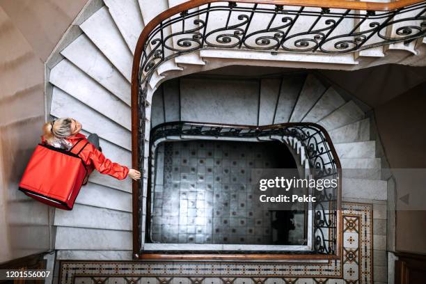 lebensmittellieferant auf der treppe im gebäude - pizza delivery stock-fotos und bilder