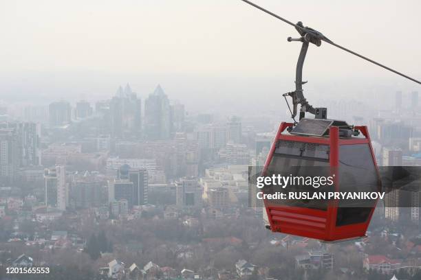 People ride a cable car as smog covers Almaty on February 10, 2020. - Snow-capped peaks used to be clearly visible from the streets of Almaty and...