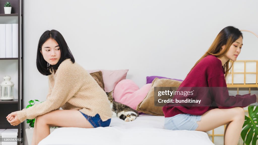 Young beautiful Asian women lesbian couple lover having stressed after conflict each other in bed room at home with moody emotion.Concept of LGBT sexuality with upset and unhappy lifestyle together.
