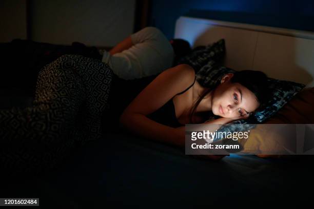 ze controleert haar smartphone voor het slapengaan - verslaving stockfoto's en -beelden