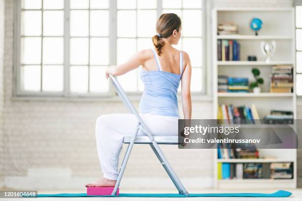 zwangere vrouw die yoga thuis praktizert - yoga chair stockfoto's en -beelden