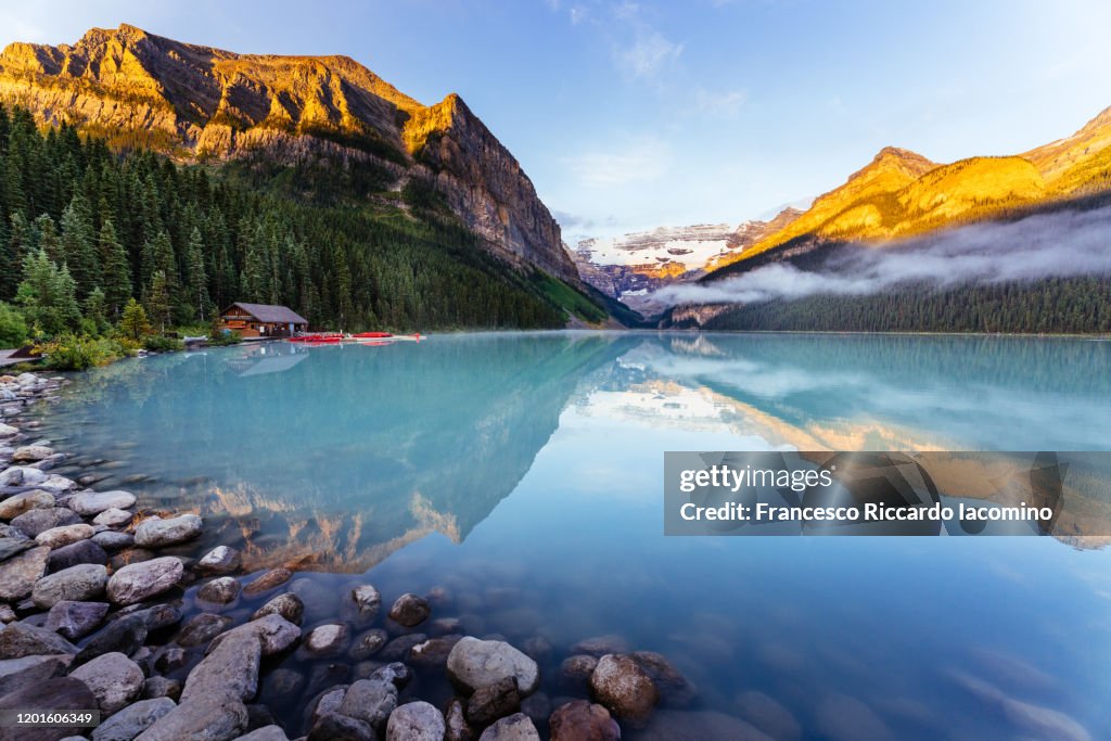 Lake Louise at sunrise, calm water and light on the mountain tops. Banff, Alberta, Canada.