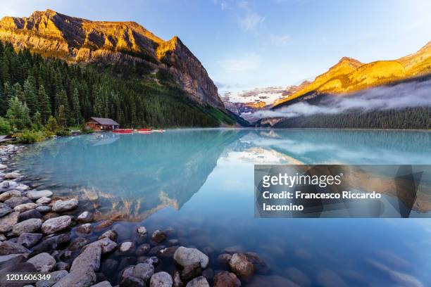 lake louise at sunrise, calm water and light on the mountain tops. banff, alberta, canada. - canada photos et images de collection