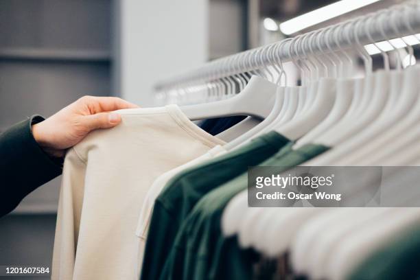 cropped hand of man holding shirt in shop - dragen stockfoto's en -beelden