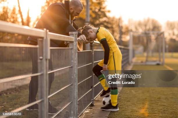 de vader die van het voetbal voetbalvoetbaldochter tijdens een spel coacht - side lines stockfoto's en -beelden