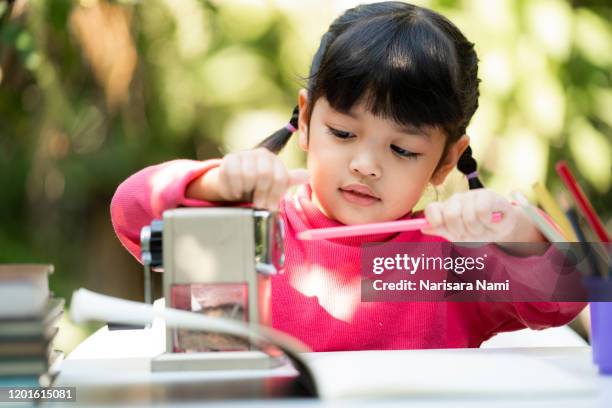 student child girl using pencil sharpener while doing homework. education concept. - scherp stockfoto's en -beelden